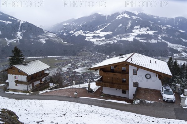 Zell am Ziller, Austria, March 11, 2019: Small apartment hotels built in Tyrolean style on the mountainside above the ski resort of Zell am Ziller. Tyrol, Austria. Cloudy day in March, Europe