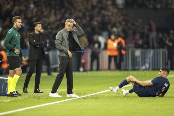 Football match, Achraf HAKIMI Paris Saint Germain right on the ground with pain in his left leg, coach Luis ENRIQUE Paris St Germain looks at him scratching his head, in the background coach MICHEL Girona FC and the fourth man on the far left, Parc des Princes football stadium, Paris