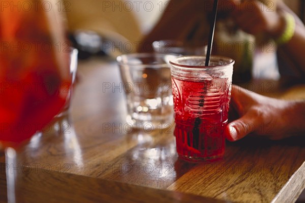 Unrecognizable person sitting at table and enjoying cool fruit cocktail on summer day in cafeteria