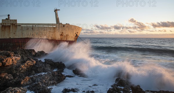 Abandoned ship in the stormy sea with big wind waves during sunset