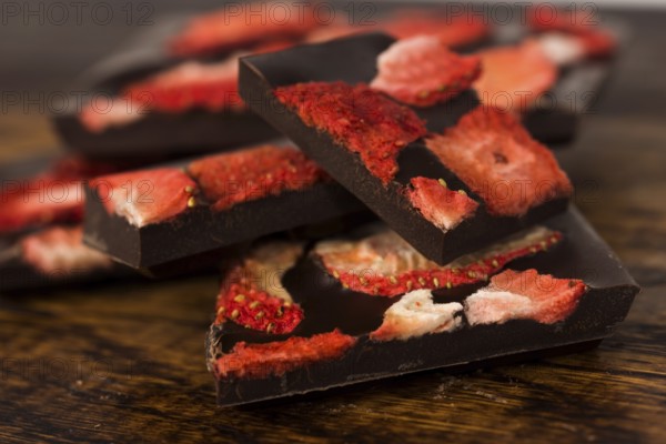 Stack of chocolate slices with strawberry on wooden background