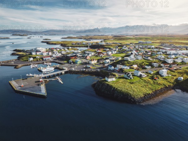 Beautiful aerial view of the Stykkisholmskirkja Harbor with Fishing ships boats at Stykkisholmur town in western Iceland. City view from Sugandisey Cliff with lighthouse. Famous colorful houses. September, autumn 2022