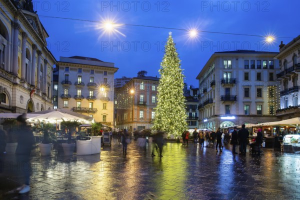 Amazing view on Christmas tree in Lugano on Reformation Square, blurred motion people Cafes (outdoor) opened in blue hour ! People posing for phoro and smiling