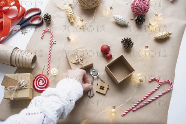 Key to house with keychain on cozy home in gift box with Christmas decor packaging. Pack present for New Year, Christmas. Building, project, moving to new house, mortgage, rent, purchase real estate
