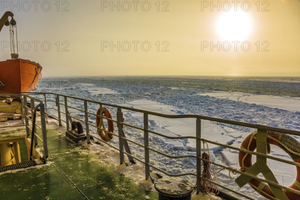 Dim polar sun in Lapland. The concept of active and extreme tourism. The strip of ice crumb spreads behind the icebreaker. The excursion to the arctic tourist cruise on the sea icebound