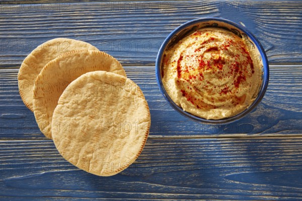 Hummus with pita bread and red pepper powder on blue Mediterranean wood table