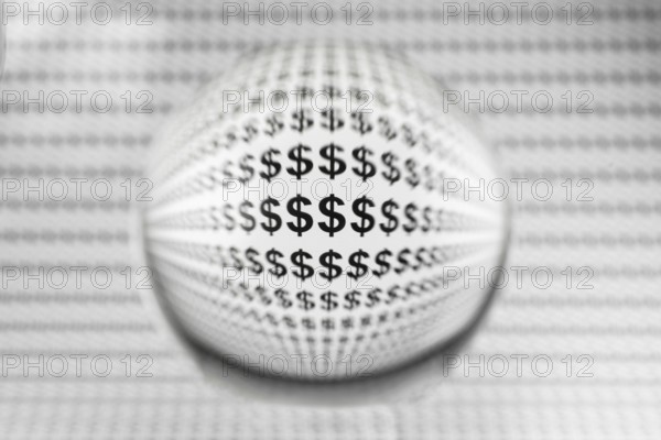 Studio shot of a glass sphere on a sheet of paper with dollar signs