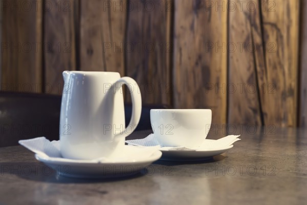 Cappuccino coffee with milk. Cup of cappuccino and jug of milk on wooden background