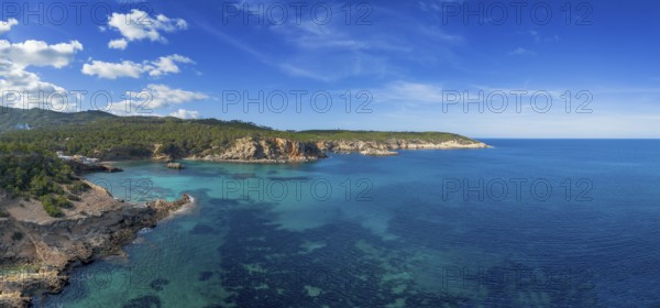 Aerial view the green and rugged hilly coast of northern Ibiza with the turquoise waters of Cala Xarraca bay