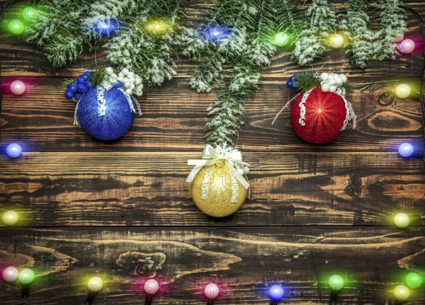Balls and garland at fir branch on wooden background