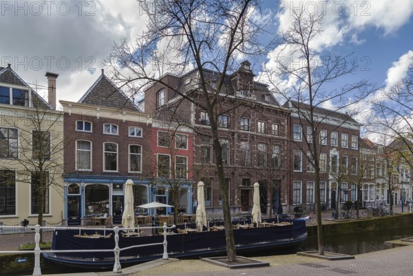 View of Delft canal with historic houses and boat, Netherlands