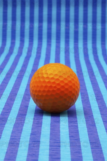 Orange golf ball on blue striped tablecloth