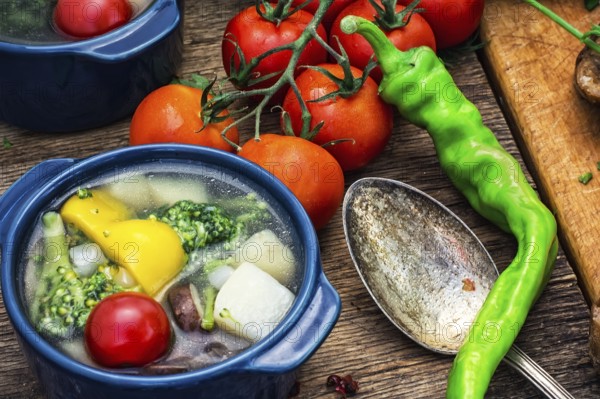 Traditional soup of fresh vegetables in blue pot on wooden background.Photo tinted