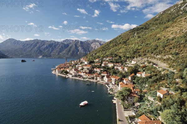 Boat is moored in the bay near the winding shore of Perast with a view of the bell tower. Montenegro. Drone.