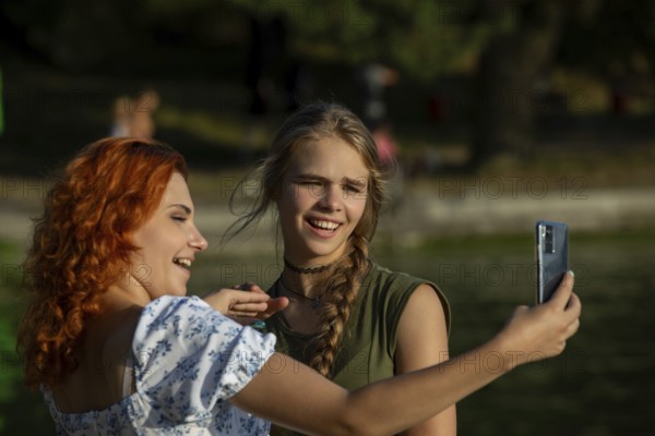 On a sunny day, two close friends enjoy each others company, laughing and taking a fun selfie outdoors