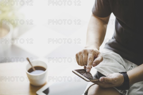 Smartphone in jungen Mann Hand mit digitalen Tablet und Kaffee