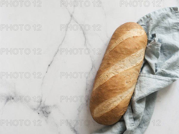 British White Bloomer or European Baton loaf bread on white marble background. Top view or flat lay. Copy space for text or design