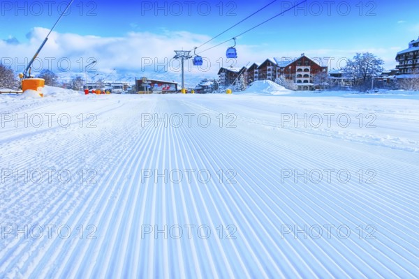 Close-up groomed snow at Bansko resort, Bulgaria panorama with ski slope and cable car lift