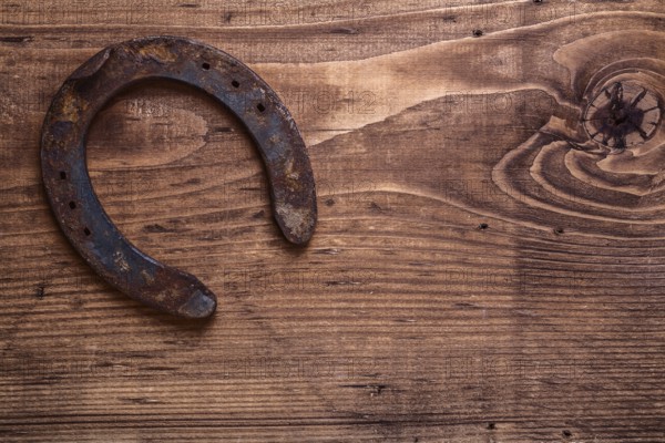 Single vintage rusted horseshoe on old wooden board with copyspace happy concept