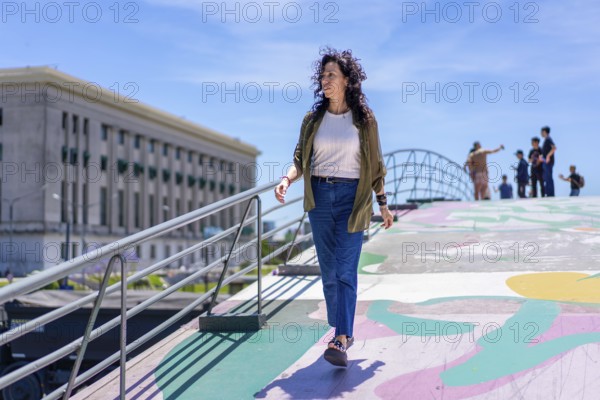 Confident woman strolling along a colorful walkway in a lively city