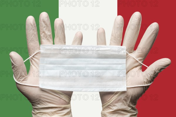 Paramedic holding respiratory face mask in two hands in white gloves on background flag of Italy. Concept coronavirus quarantine, pandemic outbreak, grippe. Medical respiratory bandage for face