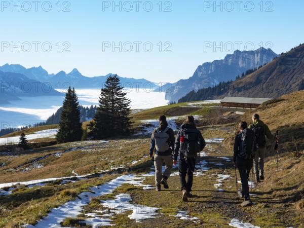 Autumn scenery with four hikers in the Swiss Alps. Very beautiful weather in the height, a big sea of fog in the valley