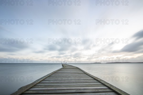 Sunrise over a lake in autumn. A wooden jetty juts into the water, while grass has established itself on the sandy beach. The lake and beach at Lake Vänern in Näs Sannar, Sweden, Scandinavia, Europe