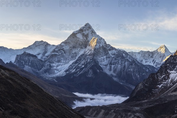 Ama Dablam mountain at sunrise and blue sky. Sun illuminates slopes. Himalayan mountains, Nepal, Asia