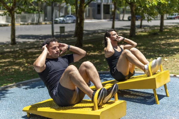 Latin men doing sit-ups in a park