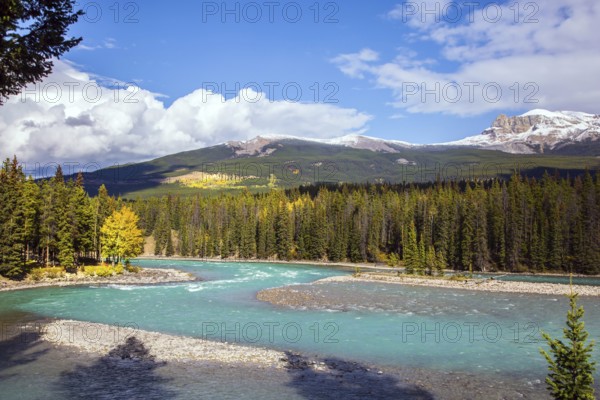 Mountain river with icy melt water from glaciers. Mountain peaks are covered with snow. The Rocky Mountains of Canada