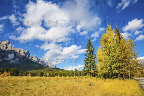The Three Sisters mountains in Canadian Rockies. Shining autumn day in Canmore. Mountain peaks and white clouds. Concept of niking