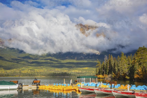 The wooden boat mooring with the moored boats. On the mooring there is elderly woman with camera. Cumulus clouds over the Pyramid mountain and Pyramid Lake