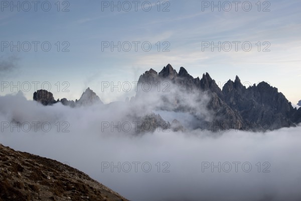 Dolomites mountain landscape rocky peaks above the clouds during sunset. Tre Cime di lavadero Italian alps, Italy, Europe