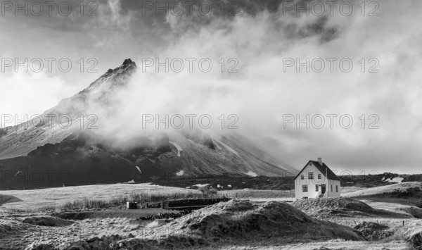 Black and white image of a Typical Icelandic winter landscape with a white small beautiful house under the mountain at Arnarstapi fishing village snaefellsness peninsula, Iceland, Europe