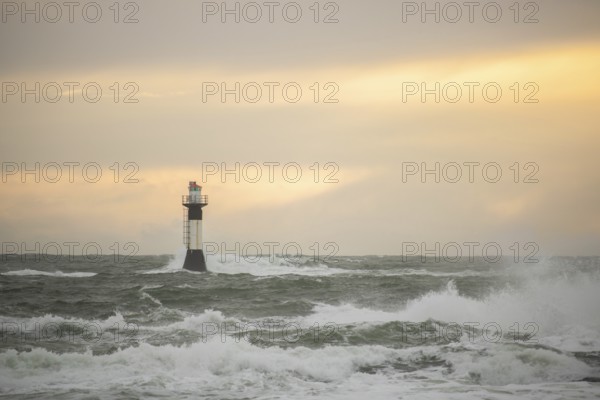 A lighthouse stands in the storm. Wild sea in the evening. Sunset on a coast with many rocks in the North Sea. Seascape in Sweden, Scandinavia