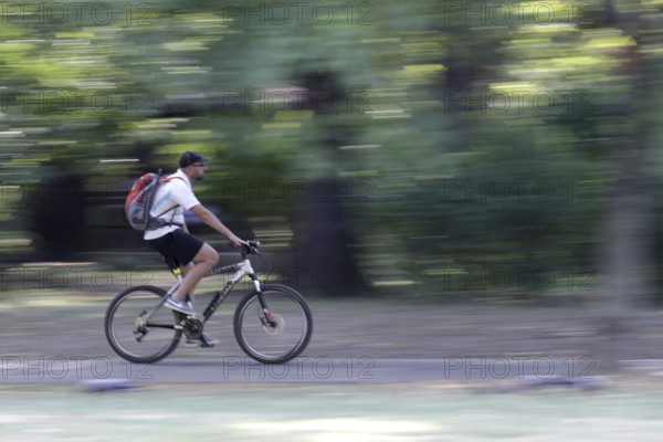 Sofia, Bulgaria - 20 August 2017 - Young man rides a bike in the park. Slow motion with blurred background of the trees