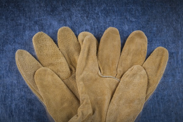 Leather brown construction gloves on scratched metallic surface close up version building concept