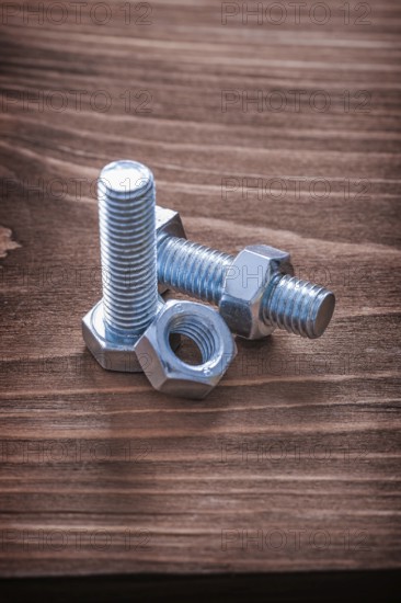 Stainless bolts and nuts on brown wooden board construction concept