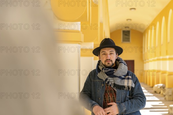 Portrait of a stylish handsome young man with a scarf outdoors. A serious man wearing a scarf, hat and a jaket looking confident at the camera