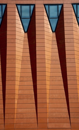 Abstract details of the exterior of a modern building with windows on a red wall