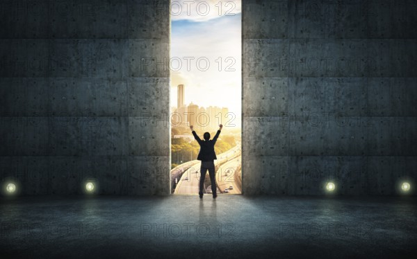 Success businessman cheering against concrete wall with huge door, sunrise scene city skyline outdoor view