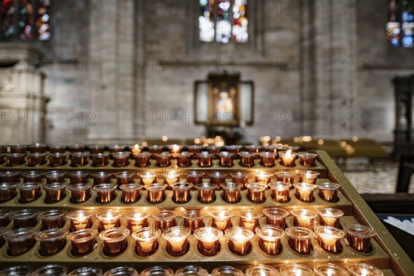 Votive candles are burning on a stand in the Duomo Cathedral. Close-up.