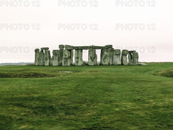 Warm-toned image of Stonehenge on a grassy field under a cloudy sky. Salisbury, England, United Kingdom, Europe