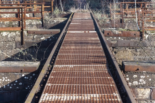 Rusted metal walkway in an industrial setting with grid pattern
