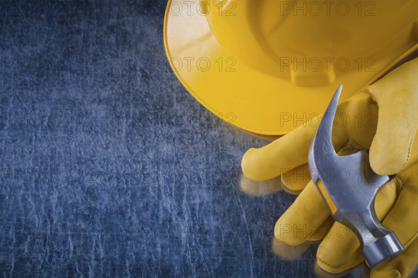 Pair of protective gloves hard hat and claw hammer on scratched metallic background construction concept
