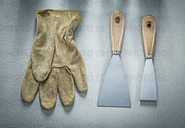 Putty knife safety gloves on concrete surface construction concept