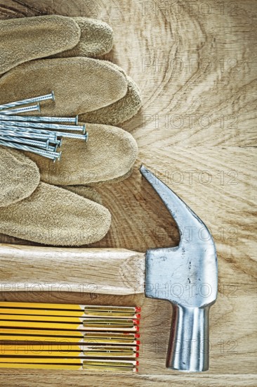 Protective gloves wooden meter claw hammer nails on wood board construction concept