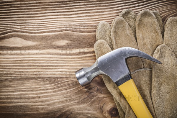 Composition of safety gloves claw hammer on wooden board