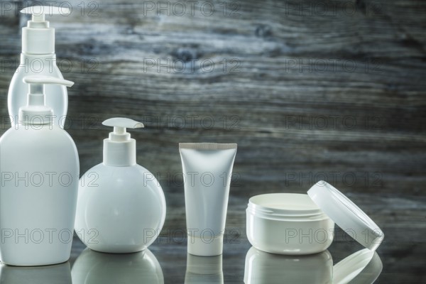 Higiene products white plasic pump dispensers tube and jar cream on vintage wooden background