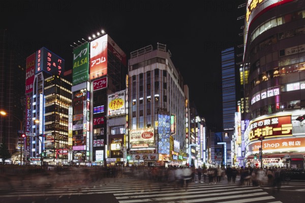 Shinjuku, Japan, May 18 2019: Neon signs illuminate Tokyo's busy Shinjuku neighborhood at night along Yasukuni-dori Ave with crowds of people, Asia